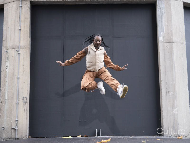 Young woman in sports clothing jumping in city