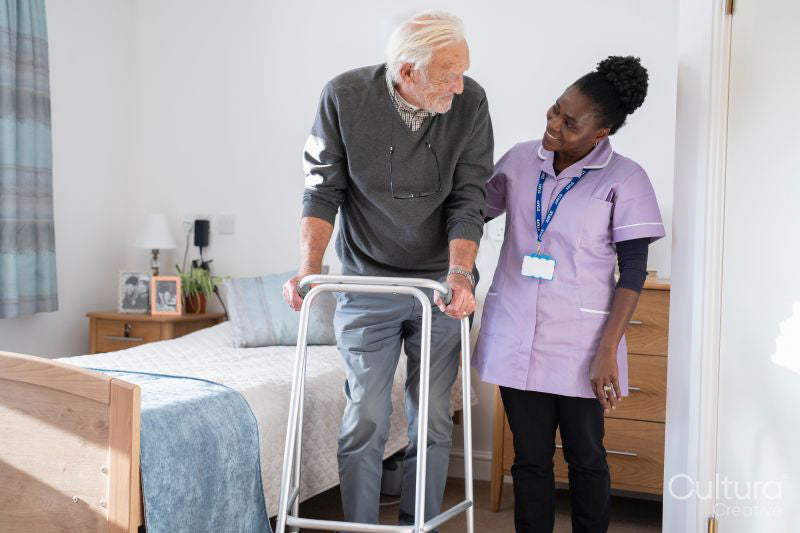 Smiling caregiver assisting senior man standing with mobility walker