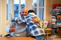 Boy hugging grandfather at table in nursing home