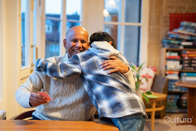 Boy hugging grandfather at table in nursing home
