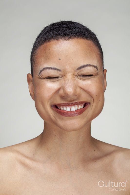 Studio portrait of shirtless woman laughing with eyes closed