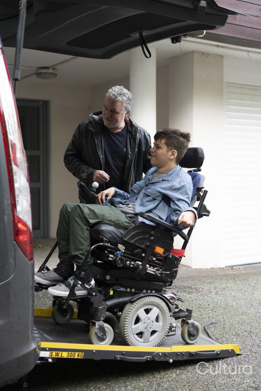 Father and disabled son using wheelchair lift
