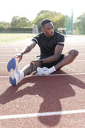 Athlete stretching legs before training at sports track