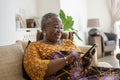 Smiling senior woman sitting on sofa with smart phone
