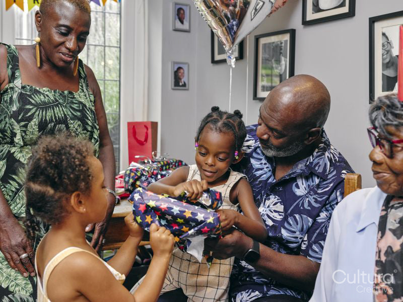 Grandfather opening birthday presents with granddaughters