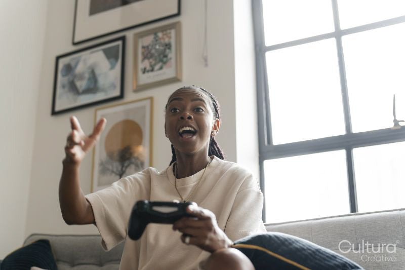 Excited young woman playing video games while sitting on sofa at home