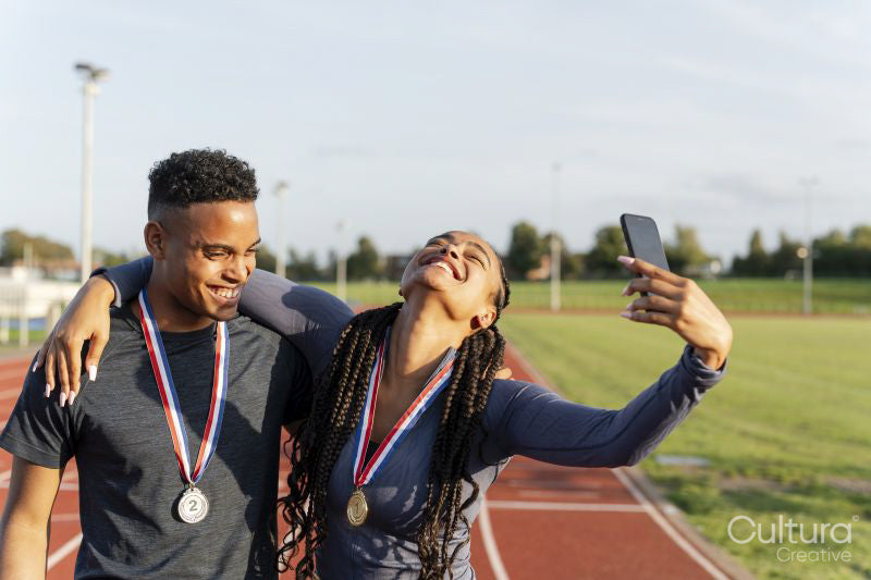 Portrait of male and female athlete celebrating with medals