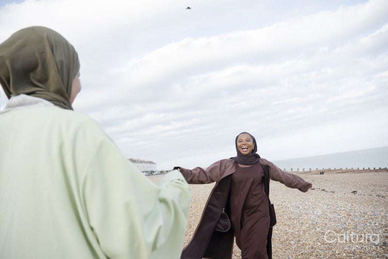 Two Muslim women greeting on beach