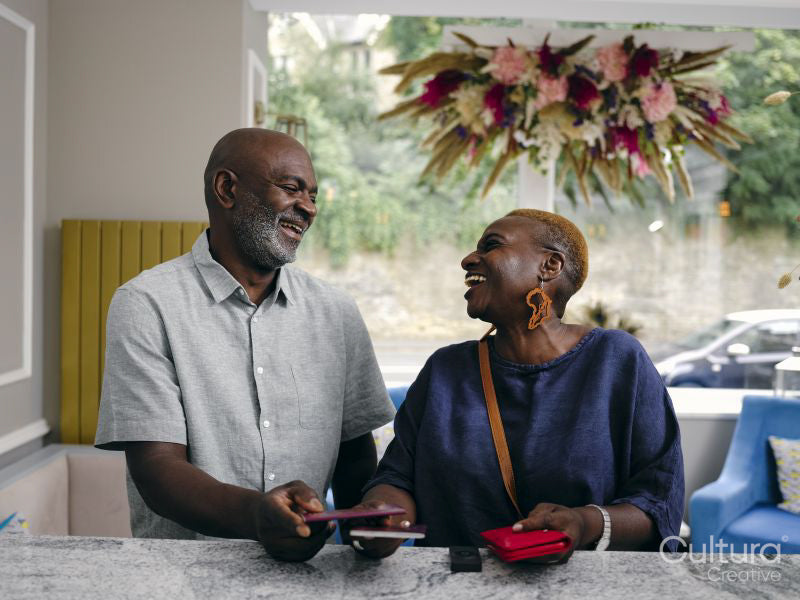 Smiling mature couple holding passports at hotel front desk