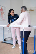 Smiling female therapist assisting senior woman walking on bars