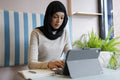 Young woman in hijab working on tablet in cafe