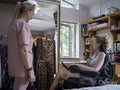 Assistant helping woman in wheelchair pick clothes