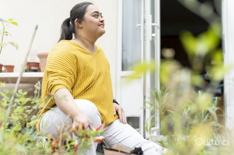 Young woman with down syndrome planting flowers in garden