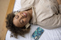 Smiling woman with headphones listening music on bed