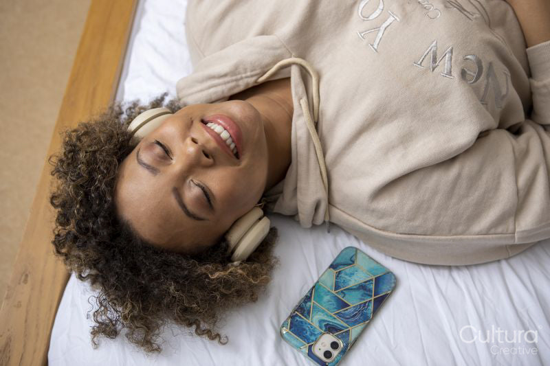 Smiling woman with headphones listening music on bed