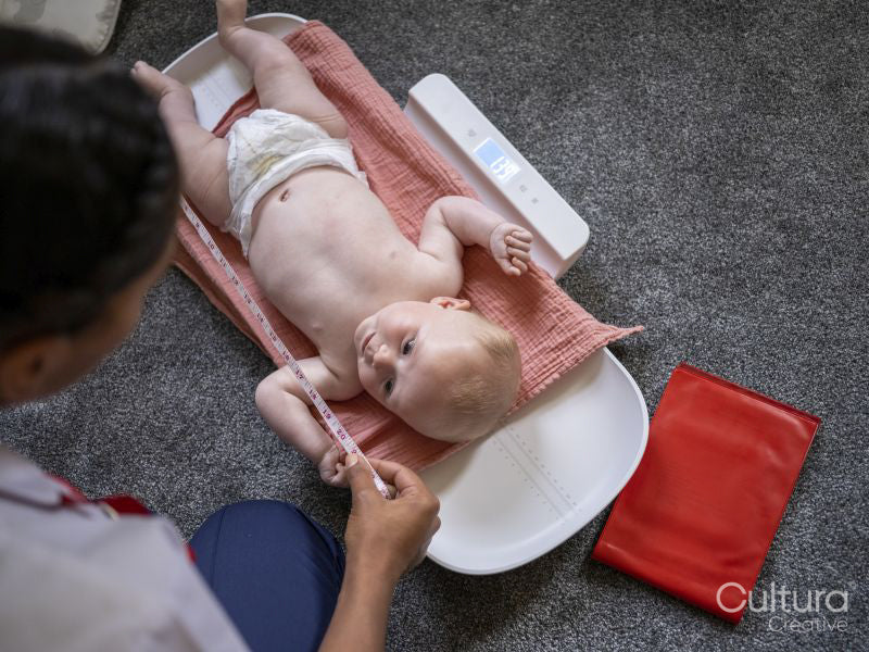 Nurse taking growth measurements of baby girl