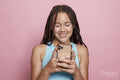 Studio shot of smiling girl with braids looking at smart phone