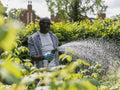 Smiling mature man watering plants in garden