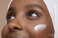 Studio shot of young woman in white hijab applying face cream