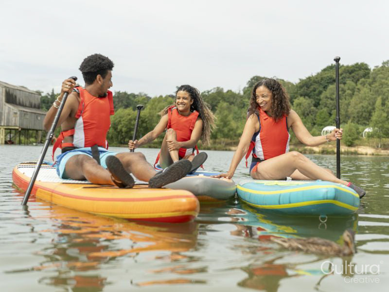 Friends having fun while paddleboarding on lake