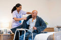 Nurse helping senior man get dressed in his room at nursing home