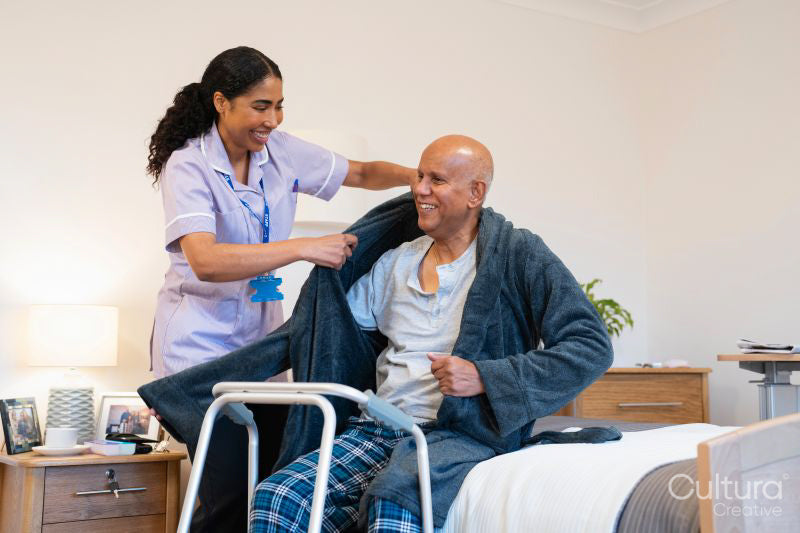 Nurse helping senior man get dressed in his room at nursing home