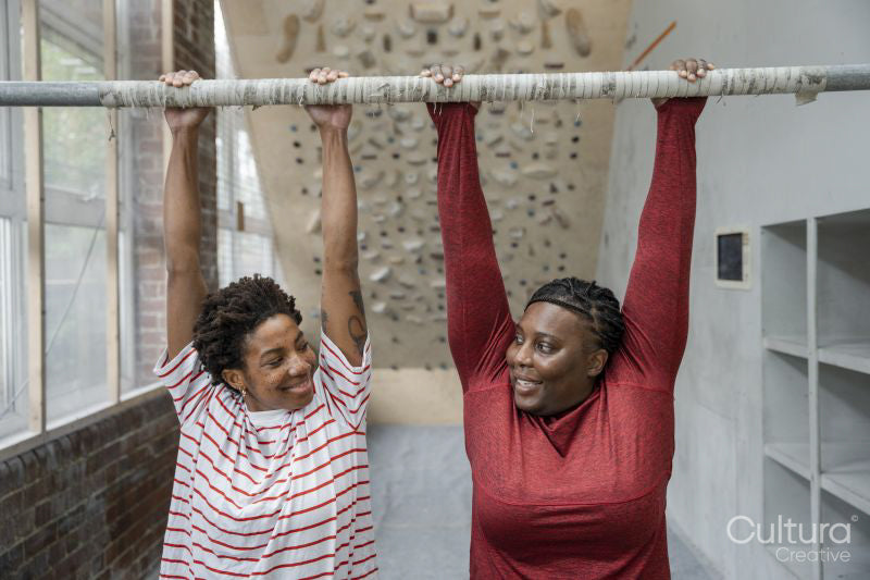 Mother and daughter doing chin-up exercise on bar