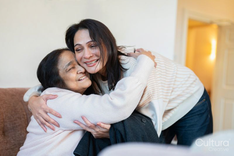 Woman hugging mother during visit in nursing home