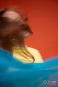 Woman in yellow dress veiled by flowing blue fabric