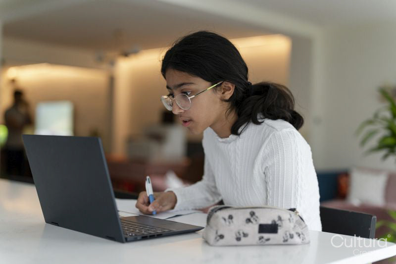Girl doing homework and using laptop in living room