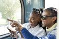 Young female friends riding city bus and using phone