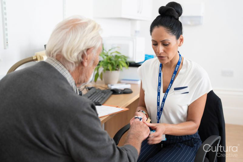 Female doctor using oximeter on senior patients finger in office