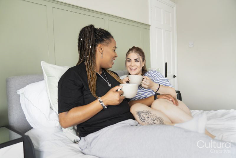 Two young women relaxing in bed