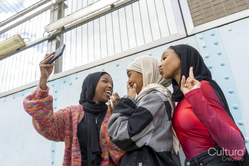 Smiling young women wearing hijabs taking selfie