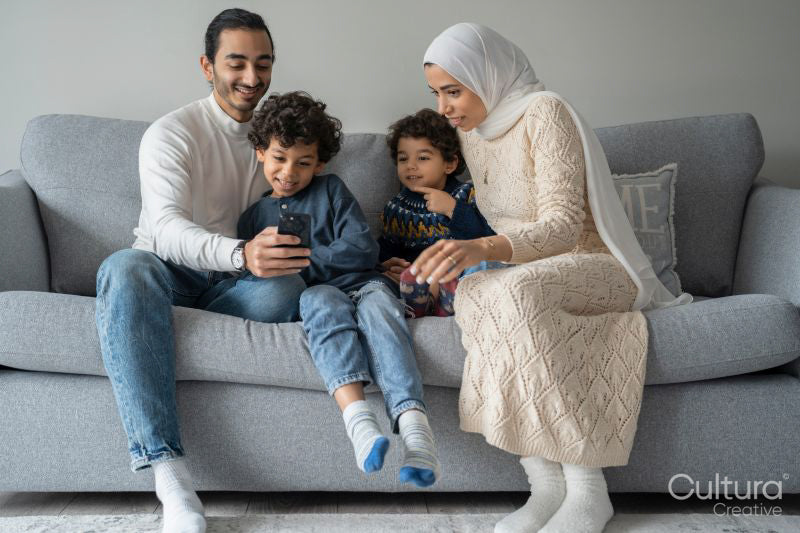 Parents and sons relaxing on sofa and using smart phone