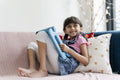 Little girl using tablet while sitting on sofa