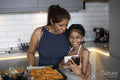 Smiling mother and daughter looking at smart phone in kitchen
