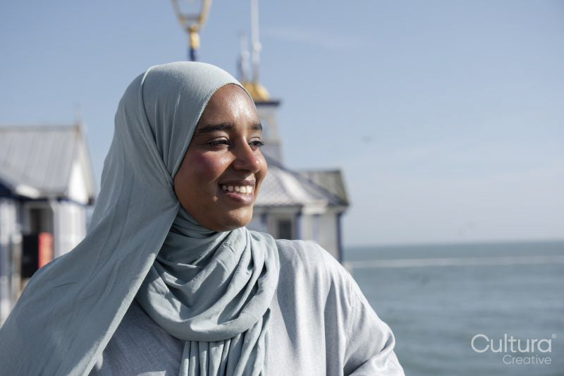 Portrait of thoughtful Muslim woman looking at sea on sunny day
