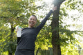 Portrait of smiling athletic woman with arm raised in park