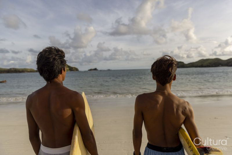 Indonesia, Lombok, Rear view of surfers looking at sea from beach