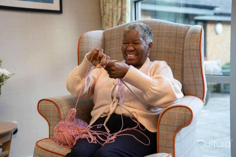 Smiling senior woman knitting in nursing home