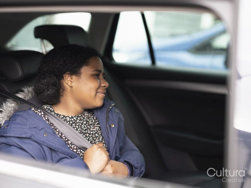Girl fastening seat belt in car