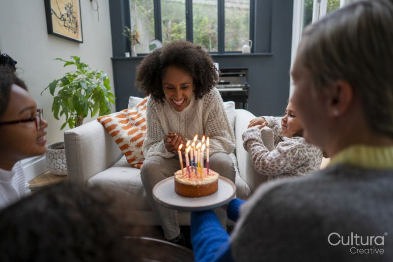 Woman serving birthday cake to female partner at home