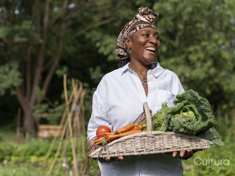 Smiling mature woman holding vegetables from garden