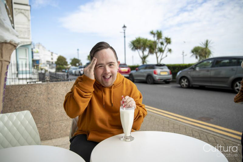 Man drinking milkshake in sidewalk cafe, portrait