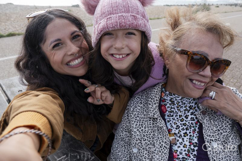 Grandmother, mother and daughter taking selfie on beach