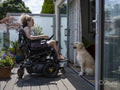 Woman in electric wheelchair relaxing on deck with dog