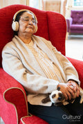 Senior woman using headphones, sitting in armchair and napping