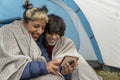 Mother and son using phone in tent