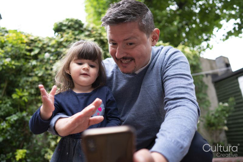 Smiling man with daughter having video call outdoors